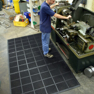 Man working machines whilst on a black mat