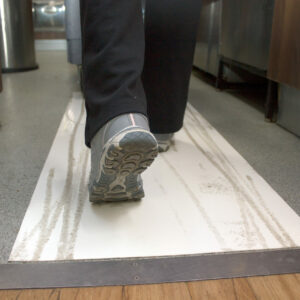 Person walking with a trolley on a sheet that captures dirt and mud