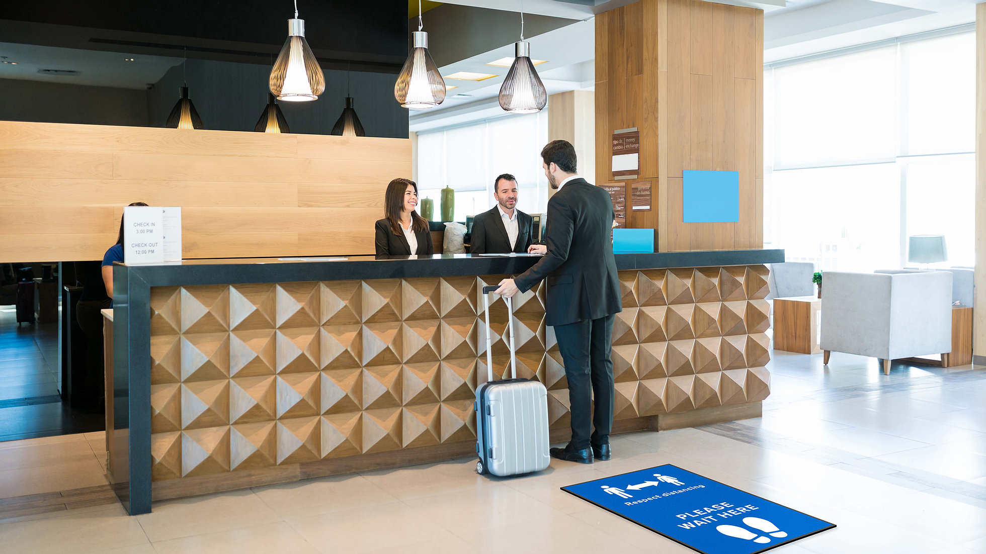 Man standing at a desk next to a blue social distancing mat